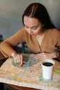 Close portrait of young woman with paper map sitting at table with cup of coffee at old town cafe Royalty Free Stock Photo