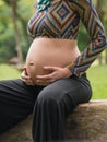 Close of pregnant modern young woman touching her belly outdoors