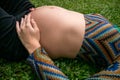 Close of pregnant modern young woman touching her belly outdoors