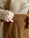 close shooting of a baby in a beige jacket and brown pants with suspenders. a small children's pen