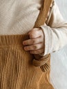 close shooting of a baby in a beige jacket and brown pants with suspenders. a small children's pen