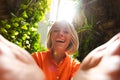 Close up shot as a girl opens her hands and is pleasantly surprised against the background of tropical greenery in the