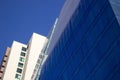 Close shot of a curved blue glass window wall of a modern and elegant corporative building, next to a yellowish classical one. Royalty Free Stock Photo