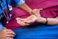 Close shot of doctor checking pulse rate to sick women by holding hands at hospital - concept of treatment, routine and