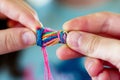 close shot of fingers intertwining embroidery floss for a bracelet