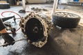 Close shot of a gearbox lying on the floor during clutch replacement, with a cr wheel in the background. Repair shop