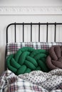 Close shot of green pillow with checkered bedclothes on the metal bed in white room