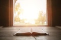 Close shot of holy bible on a wooden surface with the sun shining in the background Royalty Free Stock Photo