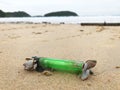 Close shot of old green plastic lighter covered with shells on a beach Royalty Free Stock Photo