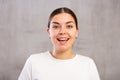 Cheery young woman posing happily against gray shadeless background