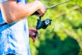 Close shot of sport fisherman reeling in line on fishing rod