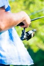 Close shot of sport fisherman reeling in line on fishing rod Royalty Free Stock Photo