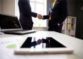 Close-shot of a tablet computer with businessmen handshaking Royalty Free Stock Photo