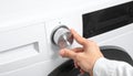 Close up of a hand turning a silver dial on a white washing machine control panel Keywords: hand, turning, dial Royalty Free Stock Photo