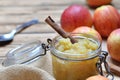 stick of cinnamon in homemade apple sauce in a glass  jar with red apples Royalty Free Stock Photo