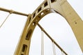 Close structural details of a self anchored suspension bridge painted yellow, overcast sky