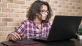 Close. teenager boy with curly brunette hair, in a plaid shirt works on a graphics tablet using a stylus