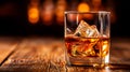 Close to the camera, a glass of whiskey with ice on a wooden table on a black background. Royalty Free Stock Photo