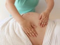 Close to the female hands of a massage therapist makes a light massage to the belly of a pregnant girl in a cosmetology room Royalty Free Stock Photo