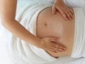 Close to the female hands of a massage therapist makes a light massage to the belly of a pregnant girl in a cosmetology room Royalty Free Stock Photo