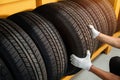 Close to the hands of a tire changer in Large warehouse of car tires, rack with customer car tires in warehouse of a tire dealer Royalty Free Stock Photo