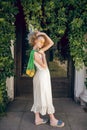 Pretty woman in a white long dress and sunglasses holding a green mesh bag in her hands Royalty Free Stock Photo