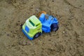 Close-up of an abandoned children's blue-green plastic toy truck inside a sand pit, a children's playground. Royalty Free Stock Photo