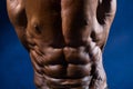 Close-up of abdominal muscles bodybuilder on a blue background Royalty Free Stock Photo