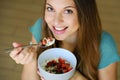 Close up from above of beautiful young woman smiling and eating skyr with cereal muesli fruit and seeds at home, focus on model Royalty Free Stock Photo