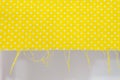 Close-up above view of yellow pola dot fabric with loose strands on one side