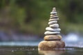 Close-up abstract image of wet rough natural brown uneven different sizes and forms stones balanced like pyramid pile landmark in