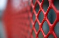Close up abstract of a red plastic fence with a blurred background. The textured lattice pattern offers a graphic element. Useful Royalty Free Stock Photo
