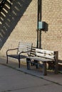 Close up abstract view of two old park benches setting along a vintage weathered brick wall with utility box Royalty Free Stock Photo