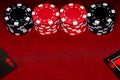 A close up of an Ace and Jack of Hearts on a black deck of cards with stacks of red and black clay chips on a red felt table.