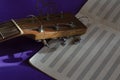 Close-up of an acoustic guitar fingerboard head and open music notebook on a blue background Royalty Free Stock Photo