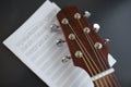 close up of acoustic guitar head with music book