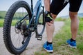 Close-up of active senior man in sportswear suffiering from pain in his knee after cycling, in park in summer. Royalty Free Stock Photo