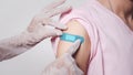 Close up adhesive bandage on woman arm after injection vaccine, medical doctor putting plaster while rubber protective gloves Royalty Free Stock Photo