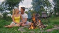 CLOSE UP: Adorable tourist couple camping in the woods cuddles by the campfire.