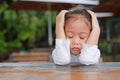 Close-up of adorable little Asian child girl expressed disappointment or displeasure on the wood table