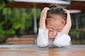 Close-up of adorable little Asian child girl expressed disappointment or displeasure on the wood table