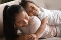 Close up adorable little daughter lying on Asian mother back