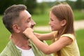 Close up of adorable little girl having fun with her loving daddy, touching his face while he is holding her and smiling Royalty Free Stock Photo