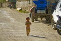 CLOSE UP: Adorable little Tibetan girl walks down dusty gravel road on sunny day