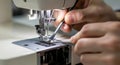 Close-up of adult hands operating sewing machine for tailoring with precision on fabric Royalty Free Stock Photo