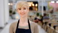 Close-up adult lady barista. Portrait waitress caucasian middle-aged woman blonde with short haircut toothy smile