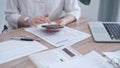 Close-up of an adult's hands with smartphone, calculator, and documents on a desk in office. Bookkeeping, finance