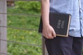 Close up of adult woman hand holding holy bible while standing with blurred public area background Royalty Free Stock Photo