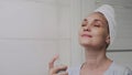 Close up Adult woman with a towel on her head applying water spray for skin hydration