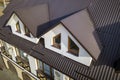 Close-up aerial view of building attic rooms exterior on metal shingle roof, stucco walls and plastic windows